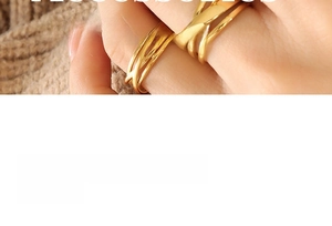 Detail of layered gold-tone crossover ring showing the woven multi-line design on finger