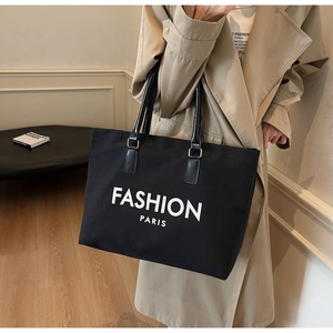 Detail einer großen schwarzen Canvas-Tragetasche mit Fashion Paris-Druck und Ledergriffen
