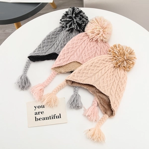 Three knit winter beanies with earflaps and tassels in pink, grey and khaki