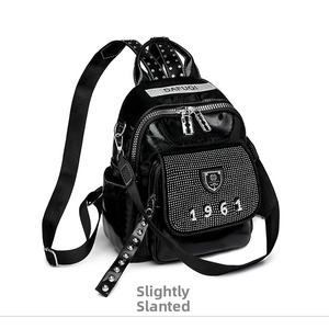 Side view of black glossy leather backpack with rhinestone 1961 detail and silver studs