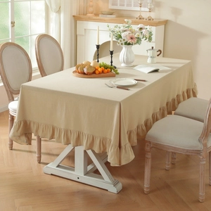 Beige washed cotton tablecloth with ruffled edges on a rectangular table in a cozy room