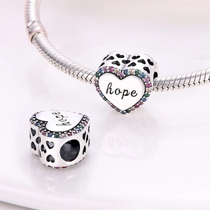 Macro shot of silver heart charm with 'hope' engraving and colorful crystals