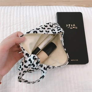 Detail of white cotton fabric pouch with black patterns and silver zipper closure
