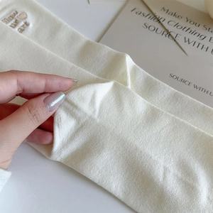 Detailed view of cream rib-knit fabric with heart embroidery and elastic stretch