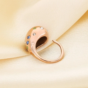 Macro shot of rose gold stainless steel ring with multi-colored crystals on silk cloth