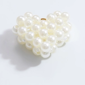 Close-up of elegant pearl heart ring with gold band on white background