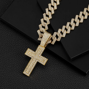 Gold plated Cuban link chain necklace with a iced out cross pendant on a dark display