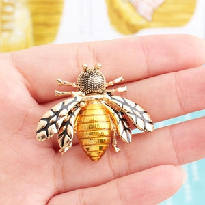 Macro shot of gold-plated bee brooch with rhinestone inlay held to show actual size