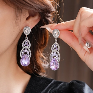 Gros plan de boucles d'oreilles en cristal violet en forme de goutte sur modèle