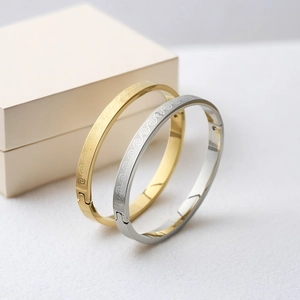 Detailed view of wave-patterned titanium steel bangles in gold and silver finish