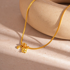 Close-up of gold chain necklace with sparkling moon and bear pendants on stone