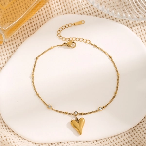 Elegant gold heart anklet with zircon accents on white ceramic plate background