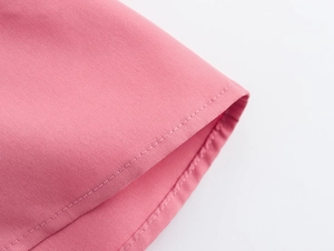 Détail du tissu tissé rose montrant les coutures précises et la finition de l'ourlet