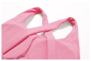 Detail of pink sports top featuring cross-strap design and reinforced stitching