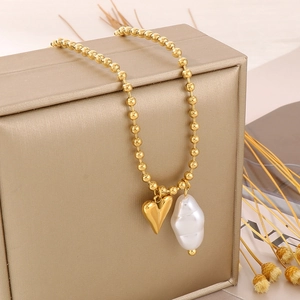 Detail view of golden heart pendant and irregular baroque pearl on bead chain necklace