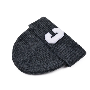 Macro detail of dark grey ribbed knit beanie showing a white letter C patch on the cuff