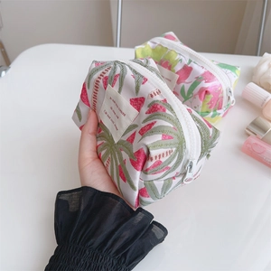 Detail of rose pink jacquard fabric makeup bag with tropical leaf pattern and zipper