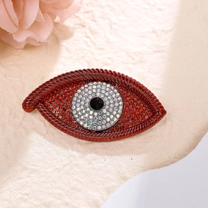 Detailed close-up of red metal evil eye brooch with sparkling red and white rhinestones