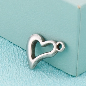 Pendentif cœur évidé en acier inoxydable argenté sur un fond en tissu bleu texturé