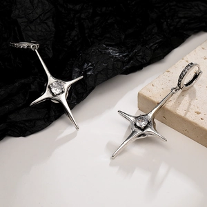 Detail of silver cross hoop earring with four-pointed star and sparkling cubic zirconia