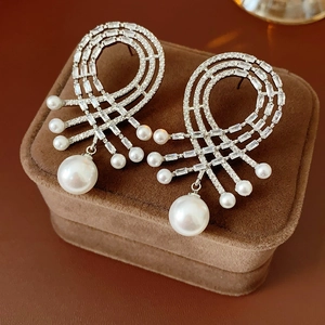 Détail de boucles d'oreilles argentées avec zircons et perles en forme de goutte sur velours