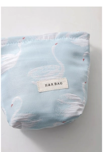 Close-up of blue swan jacquard fabric texture and brand label on small makeup bag