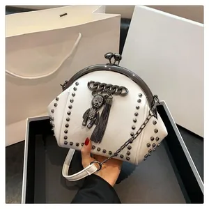 Detail of white studded shell bag with rhinestone bear charm and metal chain strap