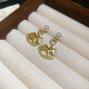 Detail of gold rocking horse earrings with pearls in a brown velvet jewelry box