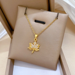 Double-layered gold maple leaf necklace with sparkling crystals in a beige jewelry box