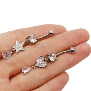 Vue détaillée de piercings de nombril en acier avec pendentifs étoile et cœur en zircon