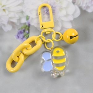 Detailed macro view of a yellow acrylic bee keychain with a metal bell and colorful chain