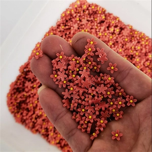 Close-up of mini red resin nail art flowers with yellow centers held in hand