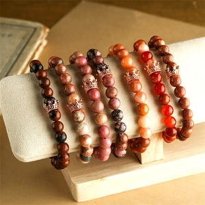 Detail von Naturstein-Armbändern mit Roségold-Kronen auf einem Schmuckständer präsentiert