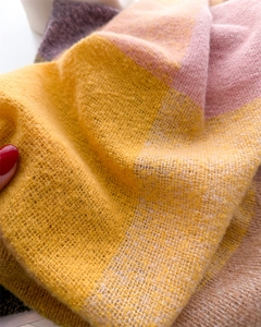Close-up of woven cashmere-feel scarf texture in yellow pink and purple plaid patterns