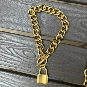 Detail of gold chunky link chain bracelet with OT toggle clasp and lock pendant