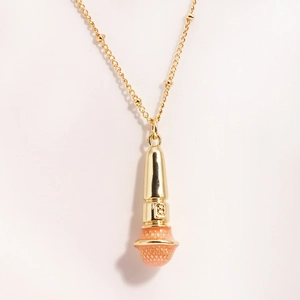 Macro shot of gold microphone pendant with textured pink finish on a stainless steel chain