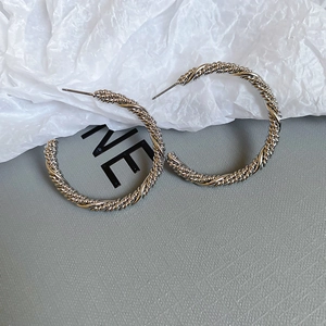 Macro detail of silver twisted rope hoop earrings with minimalist aesthetic texture