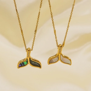 Golden dolphin tail necklace with white shell and zircon pendant on silk background