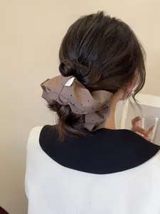 Detail showing a brown polka dot fabric scrunchie worn in a low bun hairstyle