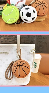 Close-up of a basketball-shaped mini coin purse keychain attached to a white handbag.