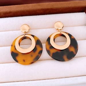 Detail of amber tortoiseshell resin hoop earrings with 18K gold plated metal accents