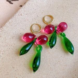 Detail of cherry-shaped earrings with red crystal drops and green glitter leaves