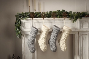 Close-up of knit Christmas stockings in grey and ivory on a white fireplace mantle