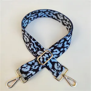 Detailed view of blue leopard pattern wide shoulder strap with gold-tone metal buckles