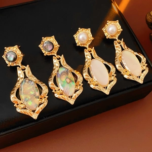 Détail de boucles d'oreilles vintage dorées avec pierres ovales en nacre et crème