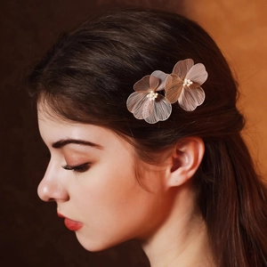 Détail d'un serre-tête de mariée avec pétales dorés et perles porté par un modèle