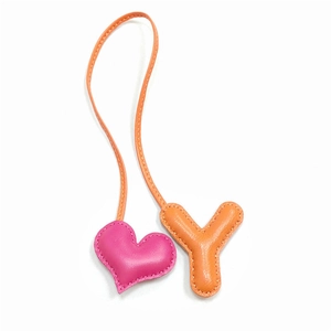 Dettaglio ciondolo borsa in pelle con cuore rosa e lettera Y arancione cucita a mano