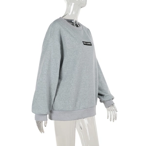 Détail d'un sweat à col rond gris avec tissu texturé et écusson WHO CARES sur la poitrine