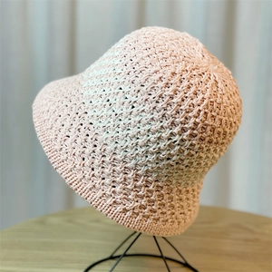 Detail view of pink straw bucket hat with fine openwork weave pattern on a stand