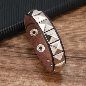 Detail of brown leather bracelet featuring silver pyramid studs and secure snap fasteners